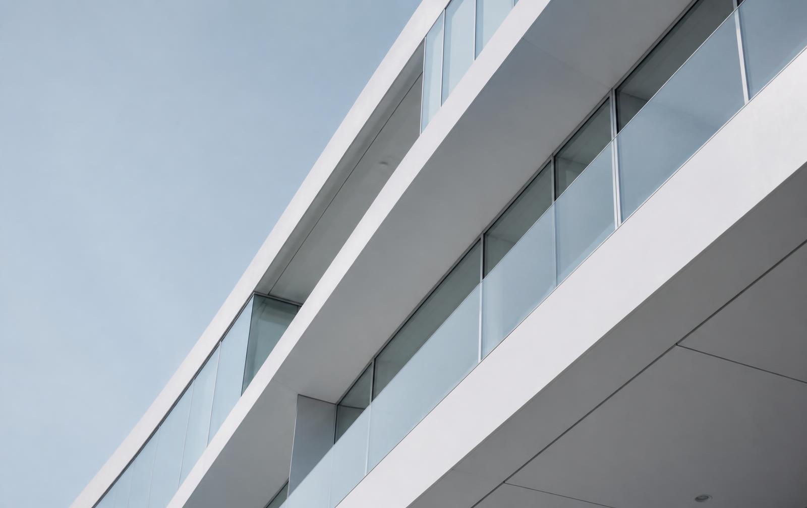 Minimalistisk fasad i glas och vitt mot ljus himmel